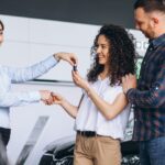 Vrolijke vrouw ontvangt autosleutels bij een shortlease-overeenkomst in een showroom