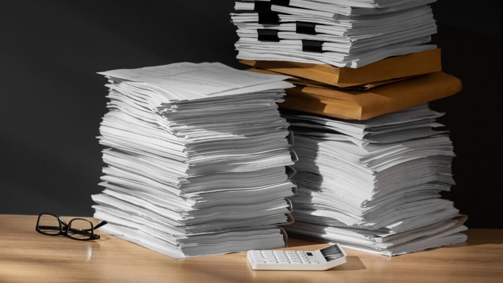 Stapel documenten en papierwerk op een bureau, symbool voor papier in marketing en communicatie