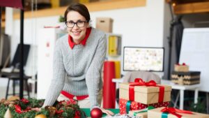 Vrouw pakt groene en eerlijke kerstcadeaus creatief in op een werktafel vol duurzame decoratie.