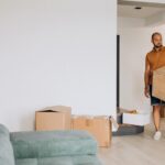 Man draagt verhuisdoos in woonkamer tijdens het efficiënt verhuizen van zijn inboedel