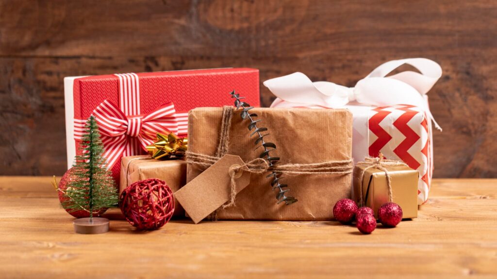 Luxe decembercadeaus met feestelijke verpakkingen in rood, goud en kraftpapier, omringd door kerstdecoratie.