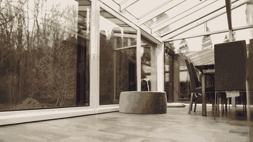 Moderne glazen overkapping met schuifdeuren en eetgedeelte, uitkijkend op een winterse tuinomgeving