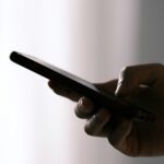 Hand houdt smartphone vast voor sms-contact, met focus op privacy en veilige communicatie