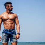 man met een summer body op het strand
