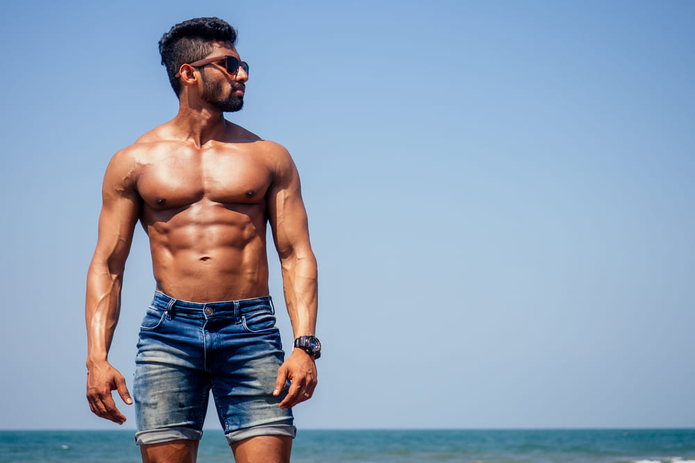 man met een summer body op het strand